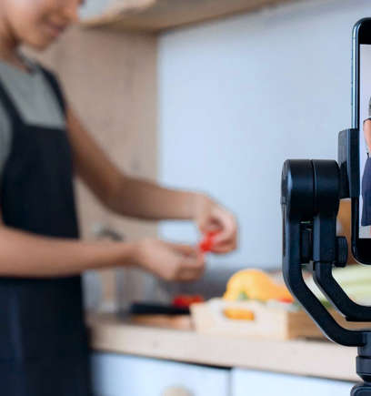 A woman working in the kitchen filming herself on her phone